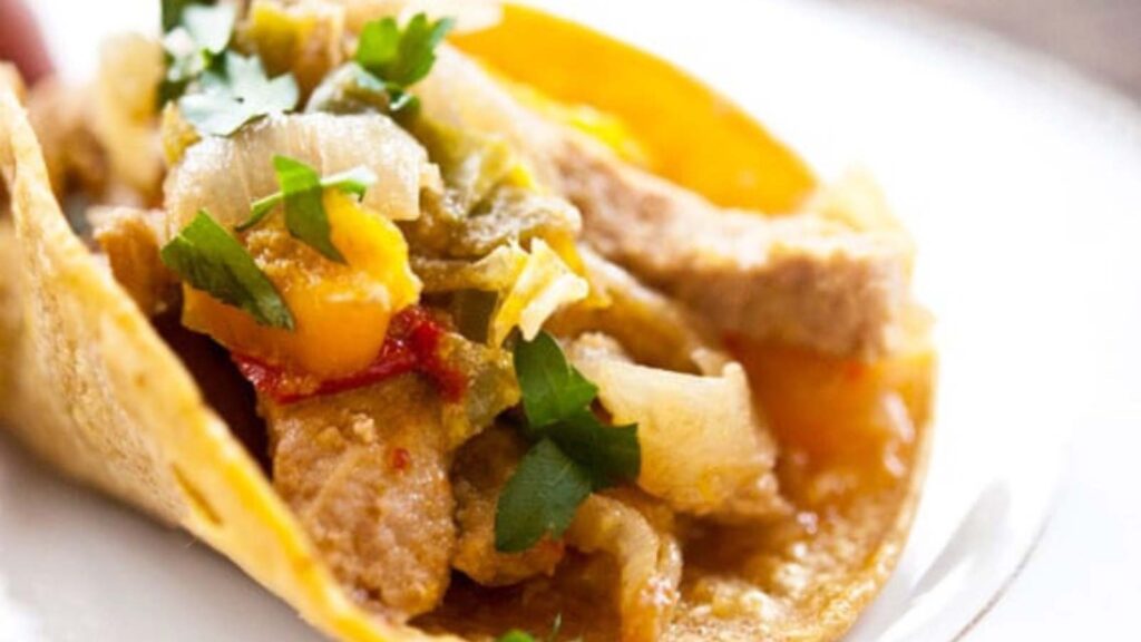 A closeup of a pork fajita on a white plate.