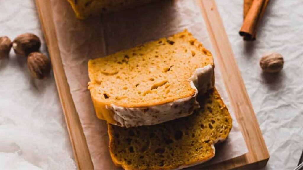 Pumpkin Bread slices with Pumpkin Spice Icing laying on a cutting board.