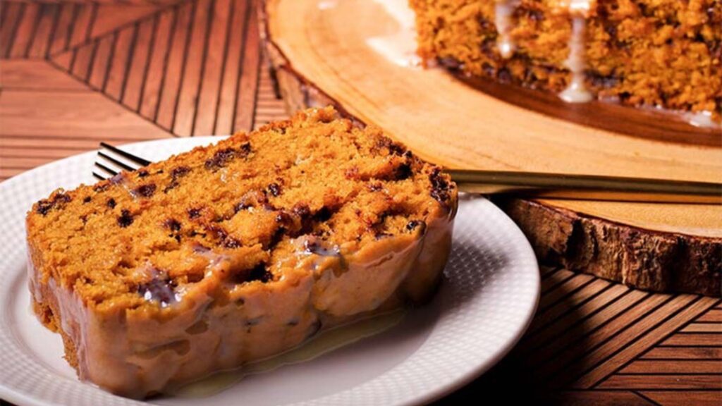 Pumpkin Chocolate Chip Bread With White Chocolate Ganache on a white plate with a fork.
