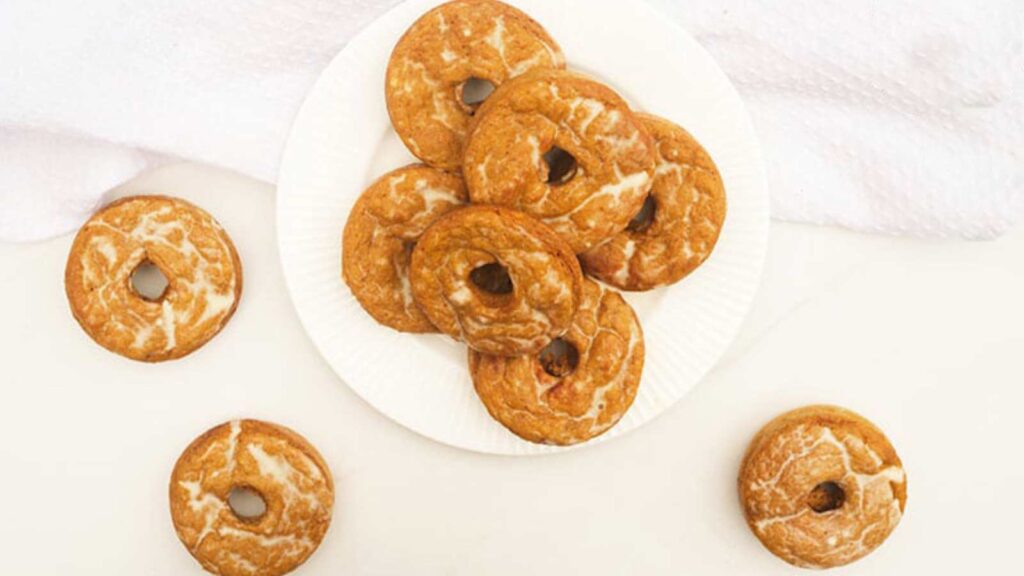 An overhead view of Pumpkin Donuts on a white plate and a white table.