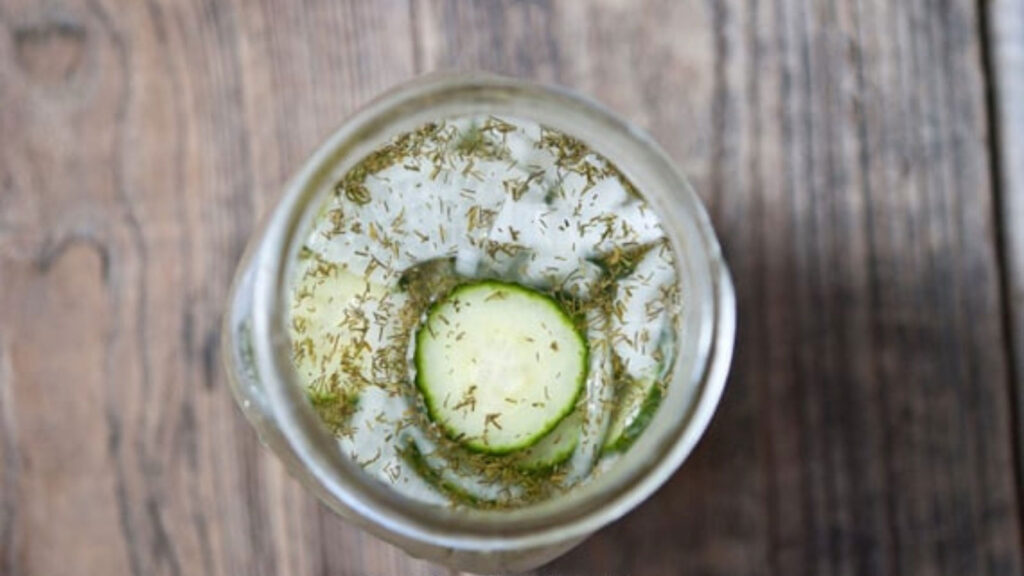 An overhead view of an open jar of refrigerator pickles.