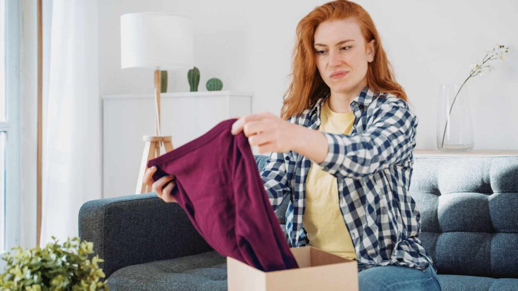 A woman opens a gift with a scowl on her face.