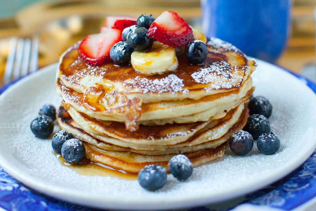 A stack of pancakes with fresh fruit on top.