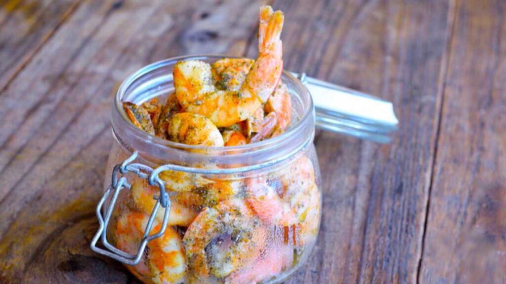 Shrimp in an open glass jar, covered in marinade.