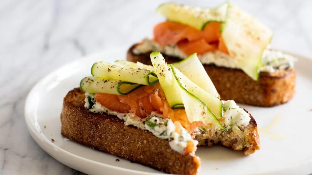 Two slices of smoked salmon sandwich on a white plate.