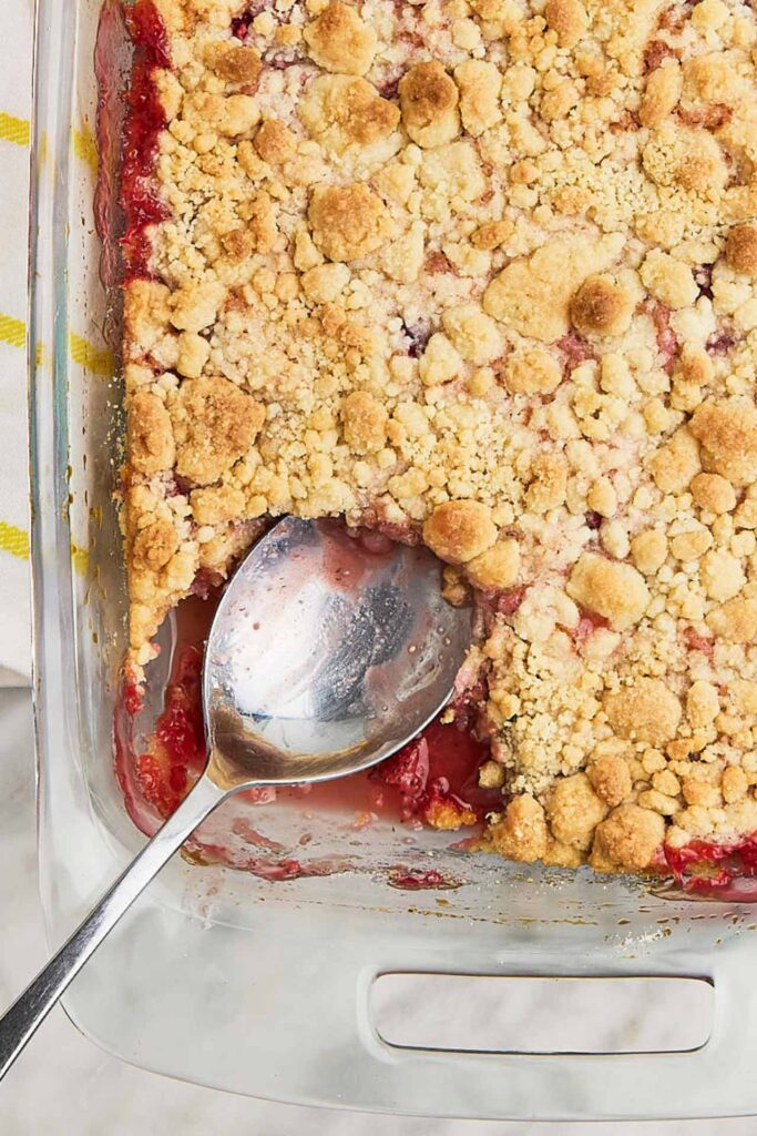 An overhead view of strawberry dump cake with a serving spoon resting in it.