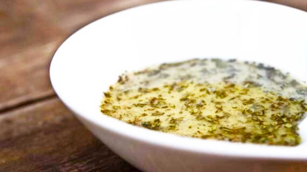 A white bowl holds a batch of Tarragon Dijon Dressing.