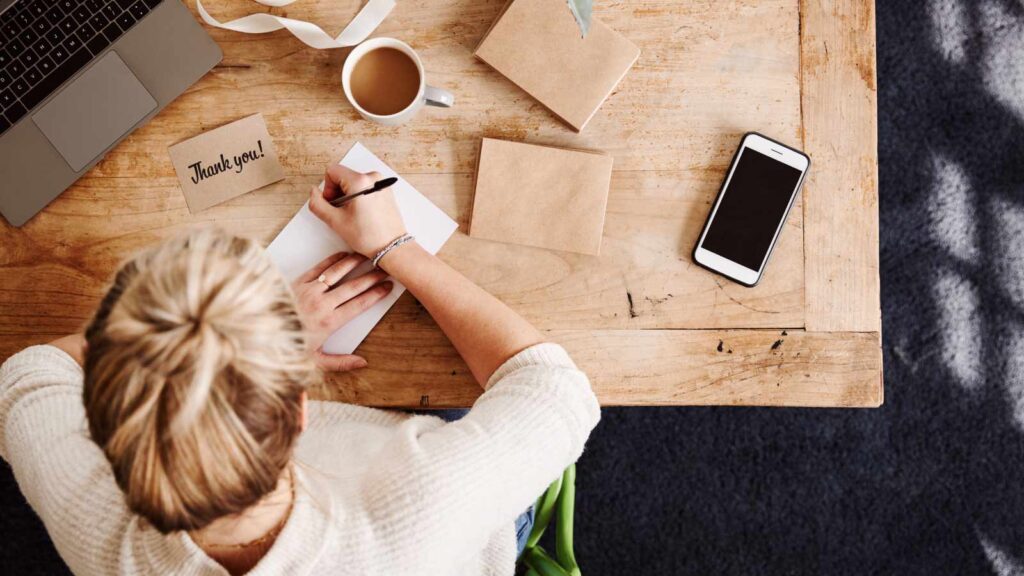 A woman writing thank you notes at a desk.
