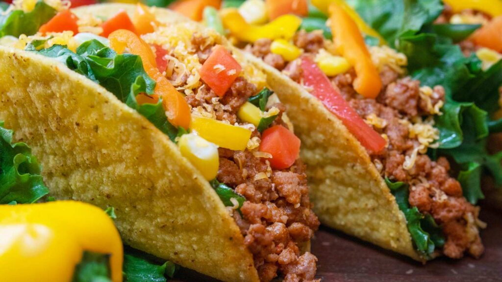 Two turkey tacos close up on a cutting board.