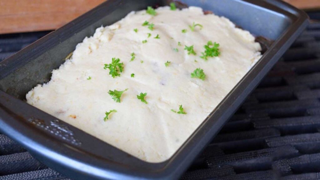 A loaf pan with just-made Turkey Vegetable Meatloaf Casserole in it. Garnished with fresh, chopped parsley.
