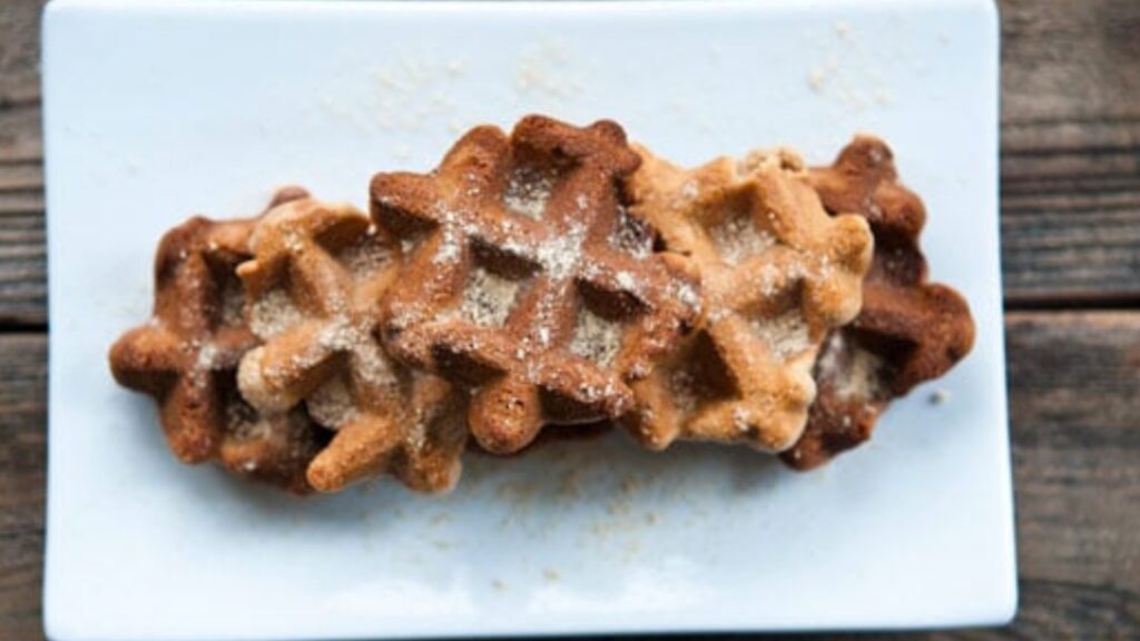 An overhead view of three waffle iron cookies on a white, rectangular platter.