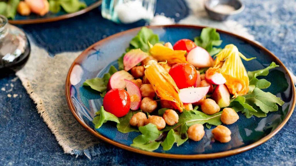 Zucchini flower salad on a blue plate.