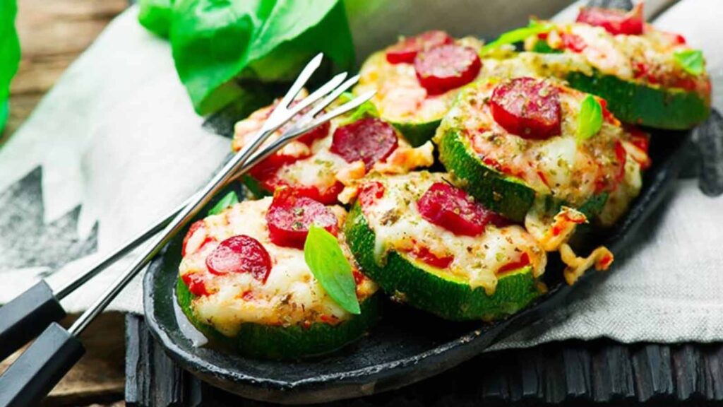 Zucchini pizza bites on a platter with two prong forks.