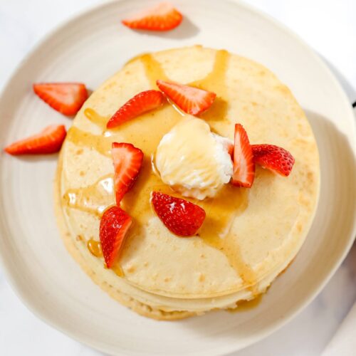 Air fryer pancakes topped with strawberries and syrup.