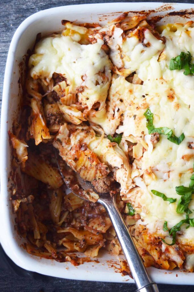 An overhead view of a white casserole dish, partially eaten, with baked ziti in it.