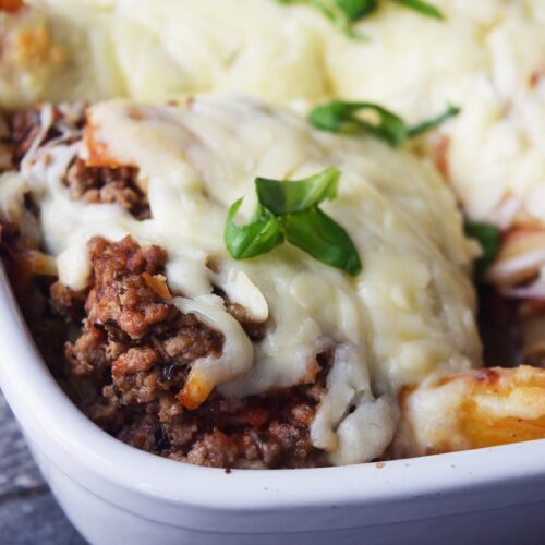 A closeup of a serving of baked ziti in a casserole dish.