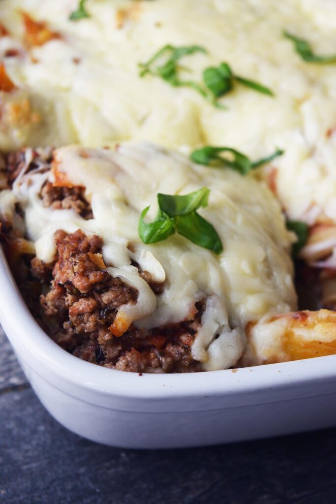 A closeup of a serving of baked ziti in a casserole dish.