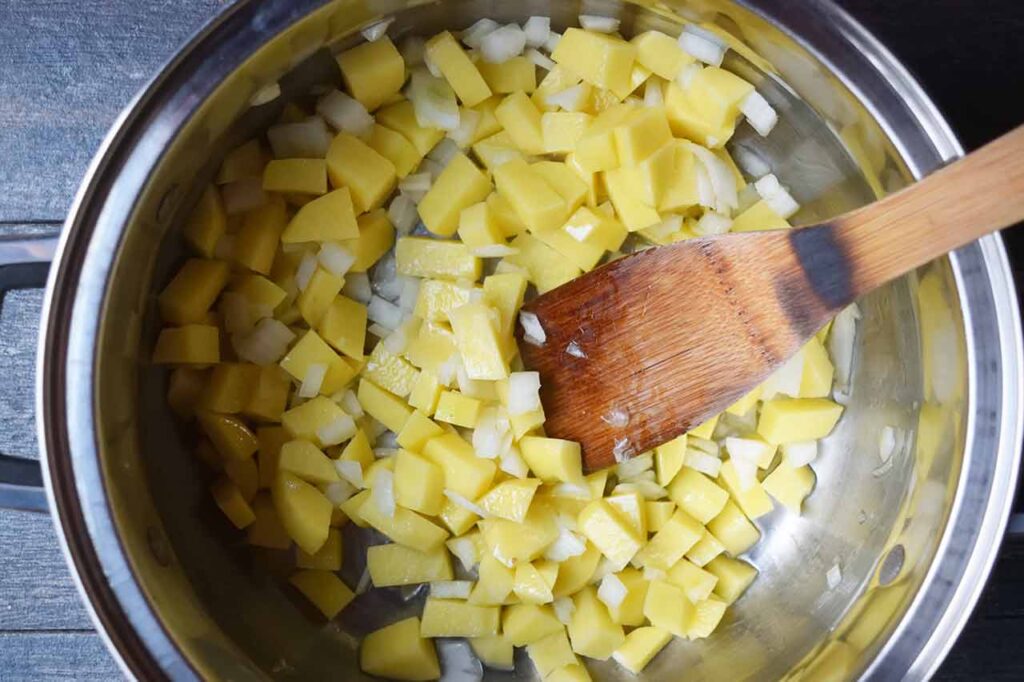 Potatoes and onions in oil in a large pot.