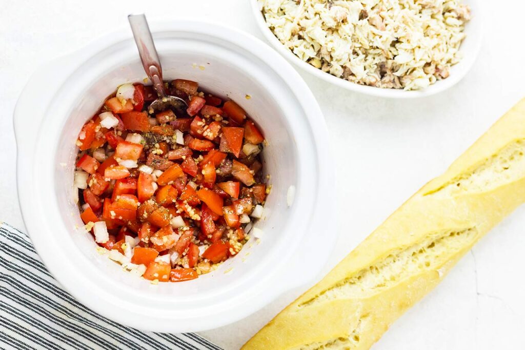 Crab mix ingredients stirred together in a white slow cooker crock.