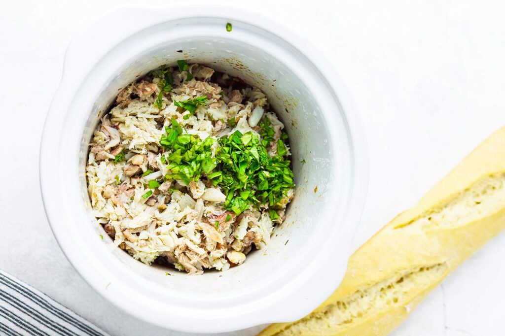 Crab meat and herbs added to to the slow cooker crock.