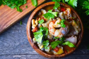 An overhead view of a wooden bowl filled with Chunky Fish Stew.