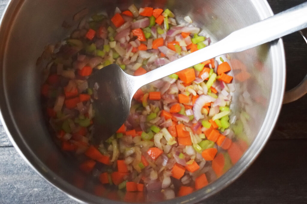 Chopped onions, carrots and celery cooking in oil in a soup pot.