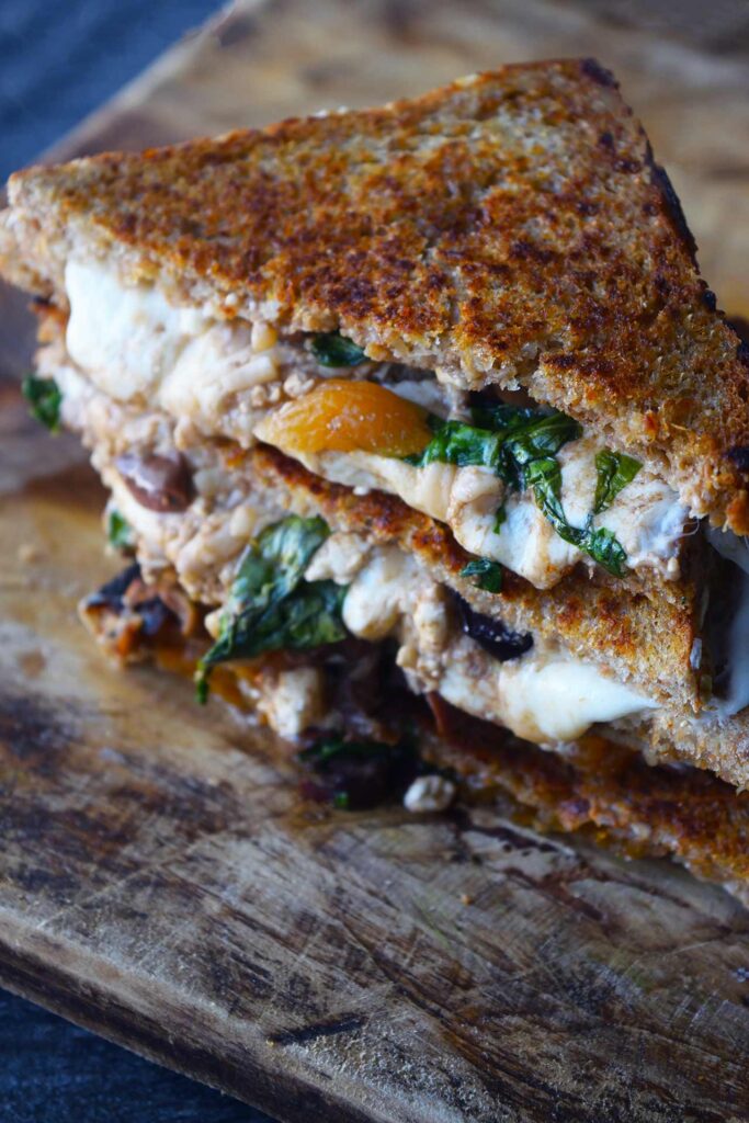 A Mediterranean Sandwich, stacked up on a cutting board.