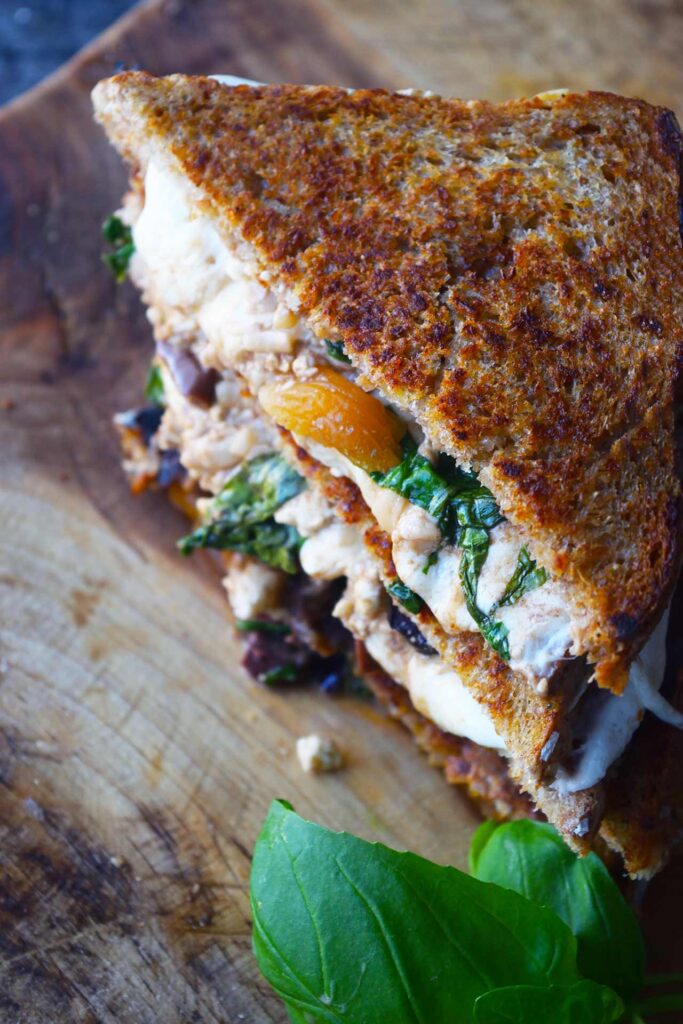 An overhead view of a Mediterranean Sandwich stacked up on a wood cutting board.