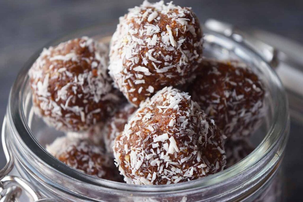 A closeup of Date And Oat Energy Balls in an open, glass jar.