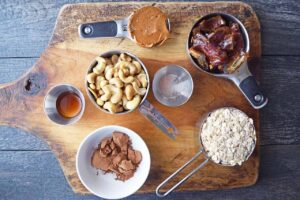 Date And Oat Energy Balls Recipe ingredients gathered in bowls and measuring cups on a cutting board.