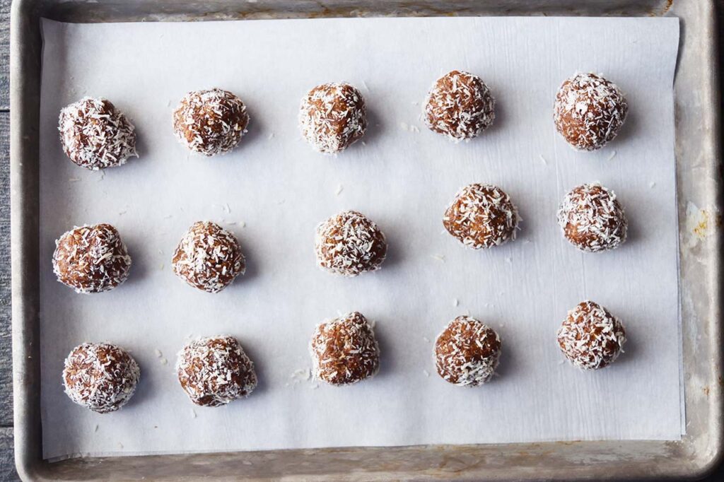 A full baking sheet of Date And Oat Energy Balls lined up in three rows.