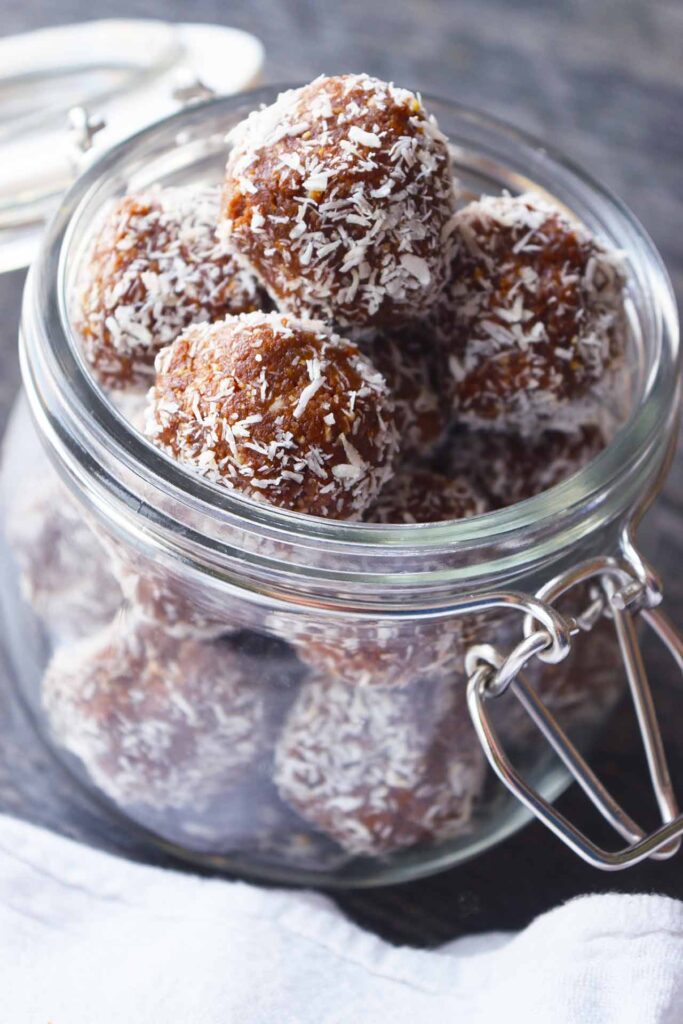 A side view of a glass canning jar, open, and full of Date And Oat Energy Balls.