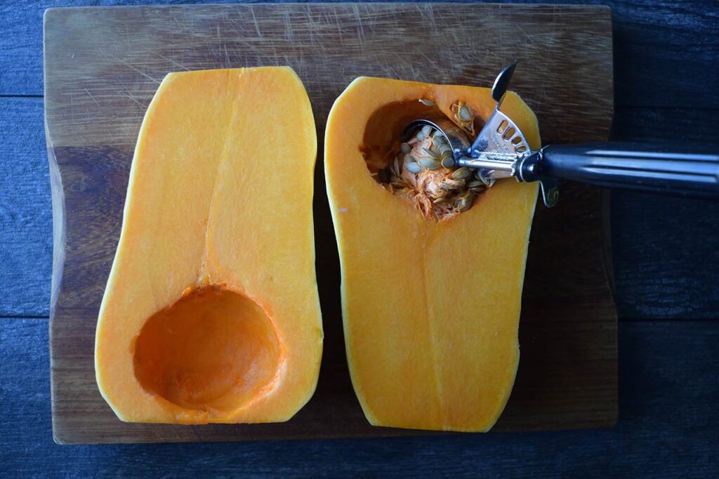 A scoop removing seeds from a butternut squash.