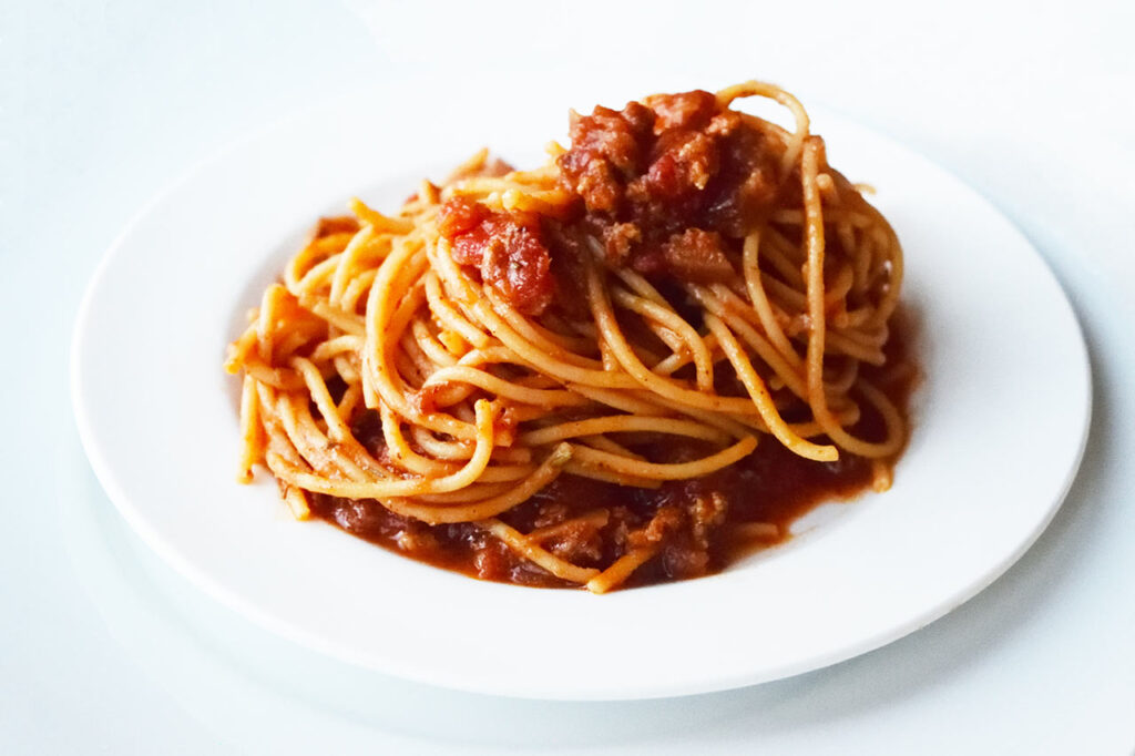 A side view of a white plate filled with spaghetti.