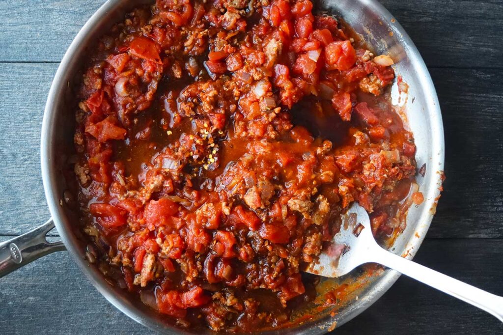 Coconut aminos, vinegar, maple syrup and crushed red pepper flakes added to a skillet of pasta sauce.