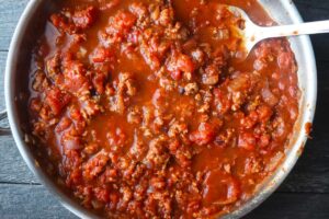 Broth added to spaghetti sauce in a skillet.