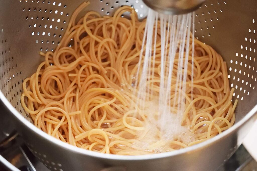 Rinsing cooked, gluten-free pasta with water.