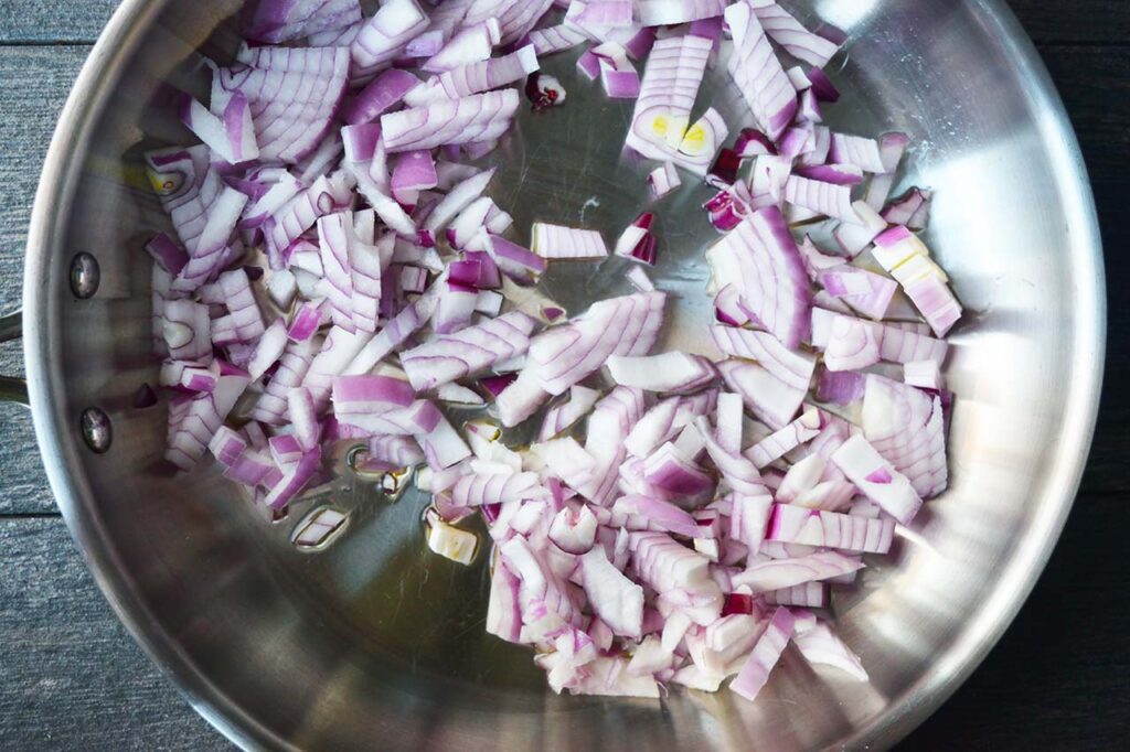 Chopped red onions in oil in a skillet.
