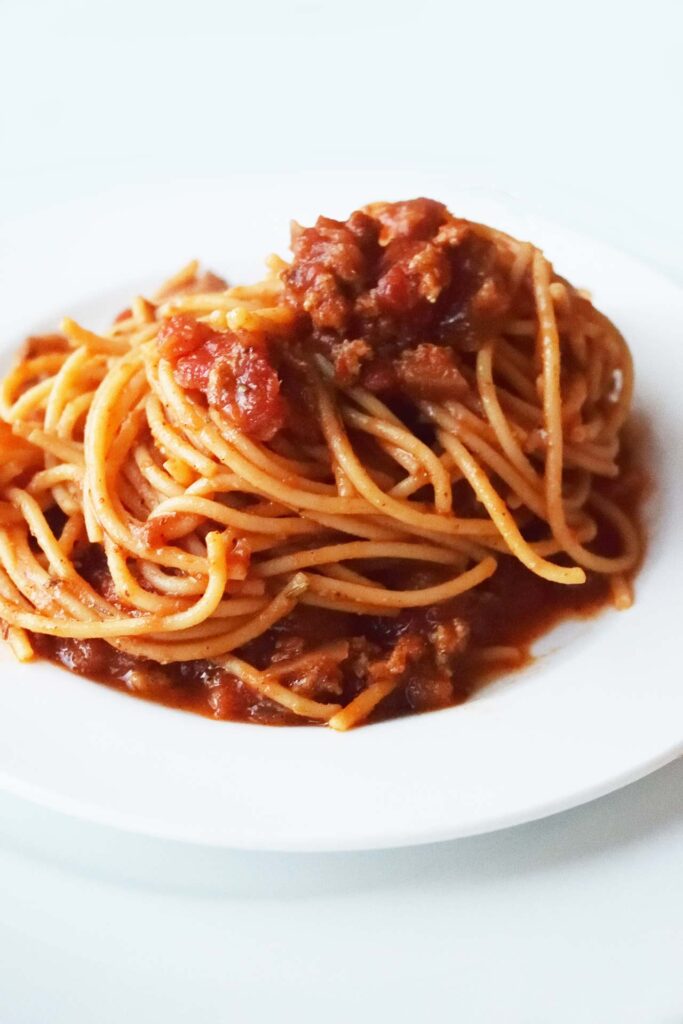 A white plate of Spaghetti on a white background.