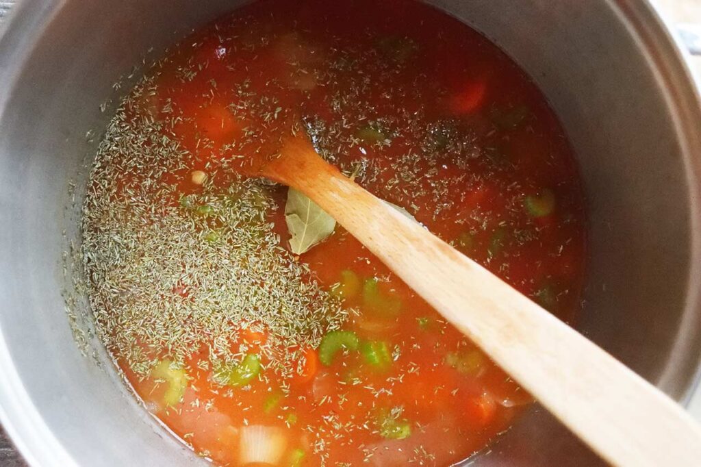 Broth and spices added to a pot of sautéd vegetables.