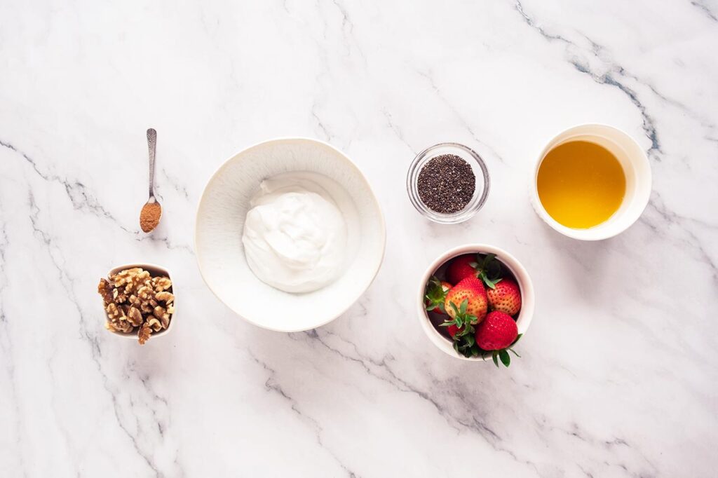 Strawberry Chia Pudding Recipe ingredients sitting on a marble countertop in individual bowls.