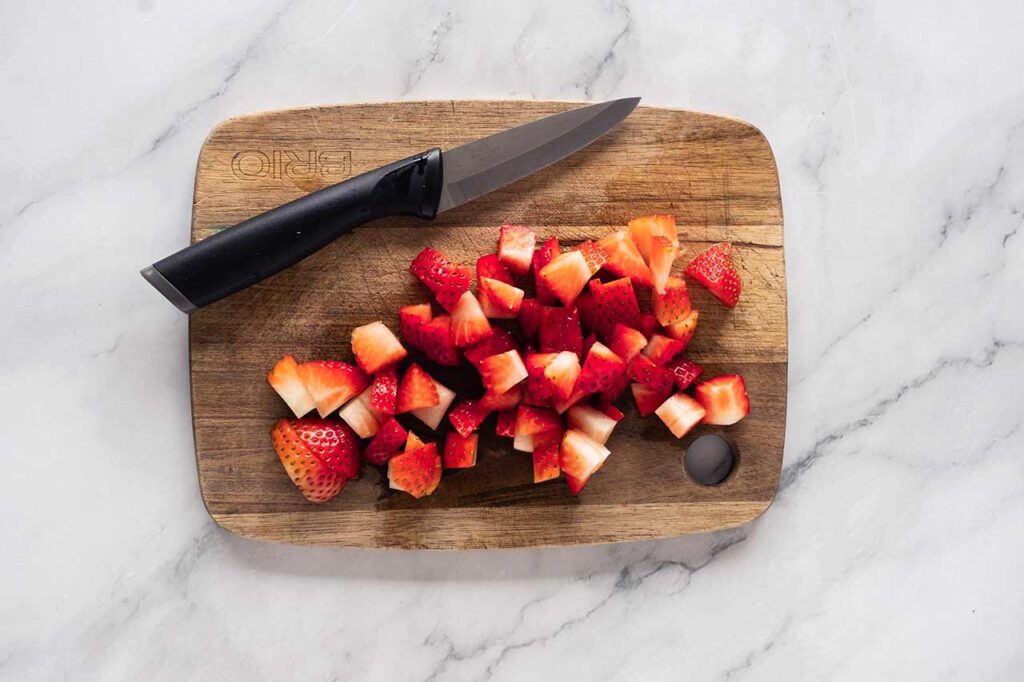 Chopped strawberries on a cutting board.