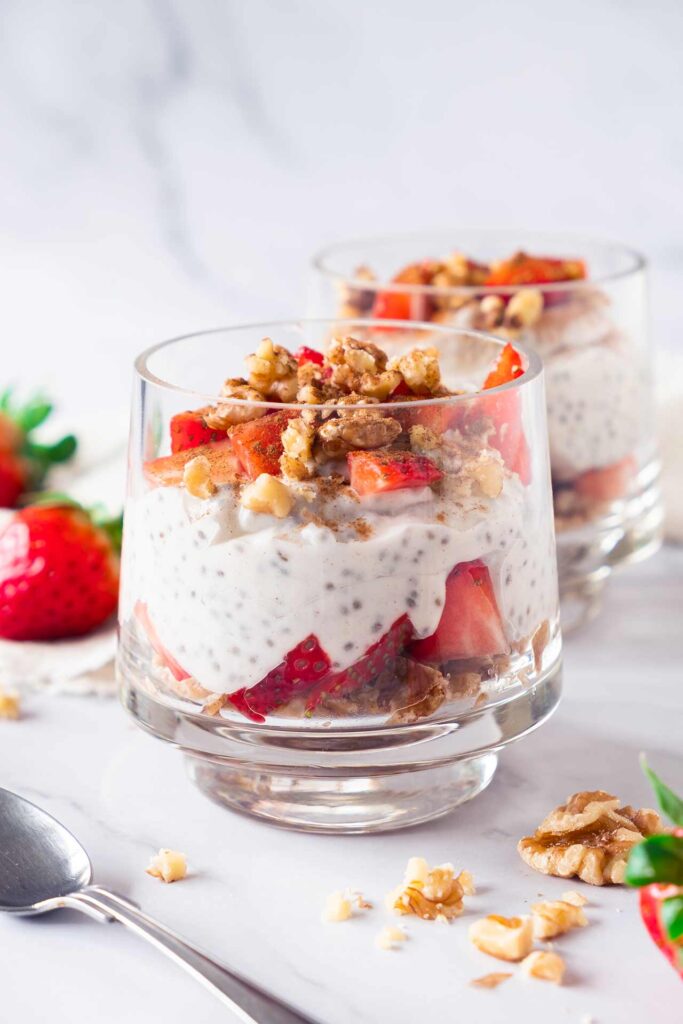 Strawberry Chia Pudding in two glasses topped with chopped walnuts.