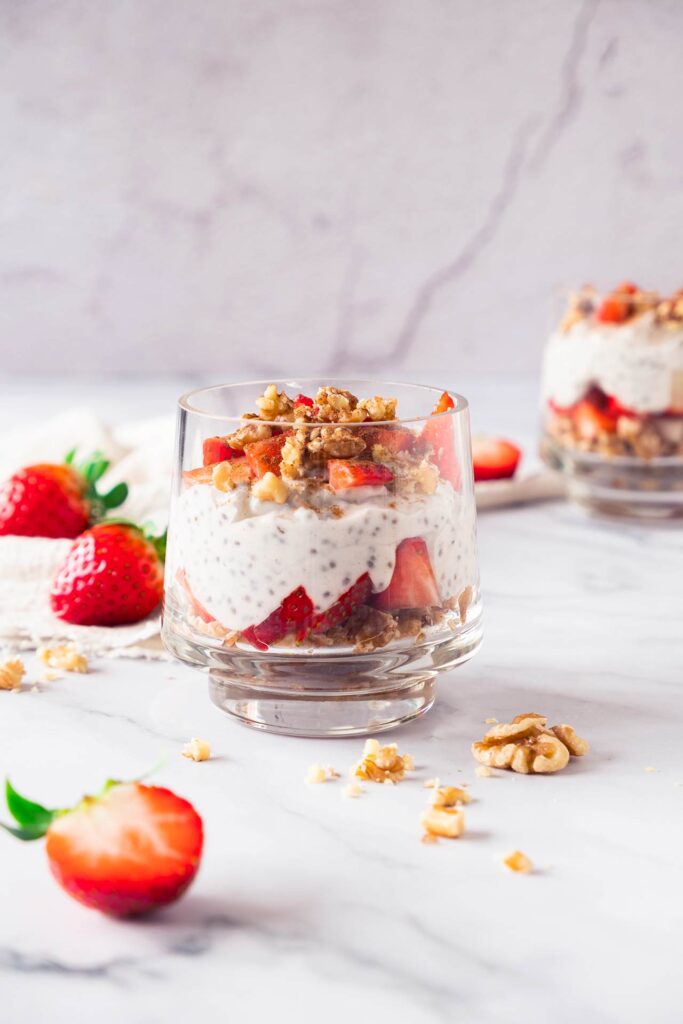 A side view of a clear glass filled with Strawberry Chia Pudding.