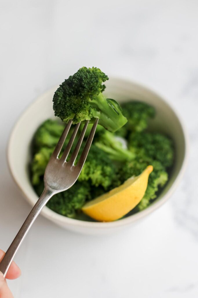 A fork holds a broccoli floret.