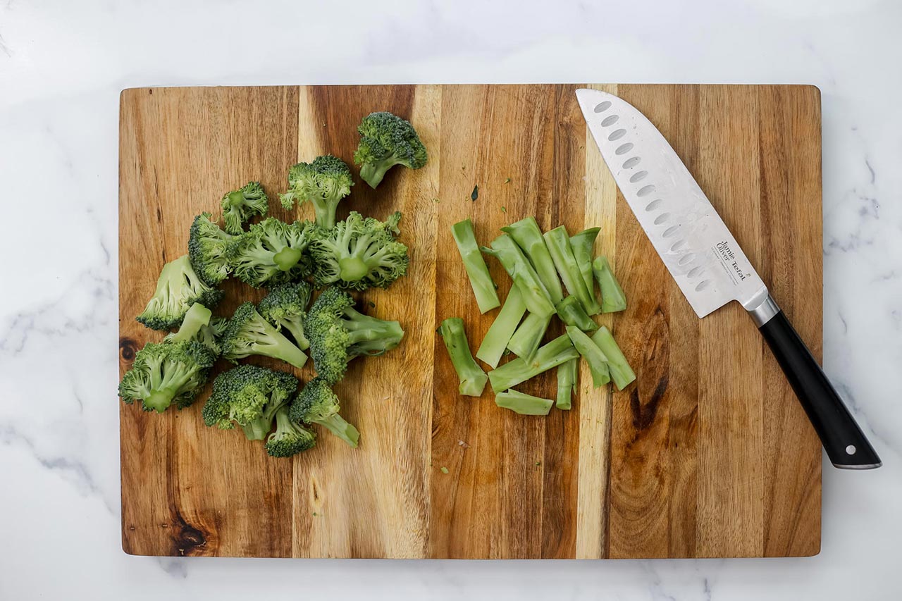 Chopped broccoli on a cutting board with a knife.