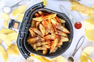 Raw, seasoned fries in an air fryer basket.