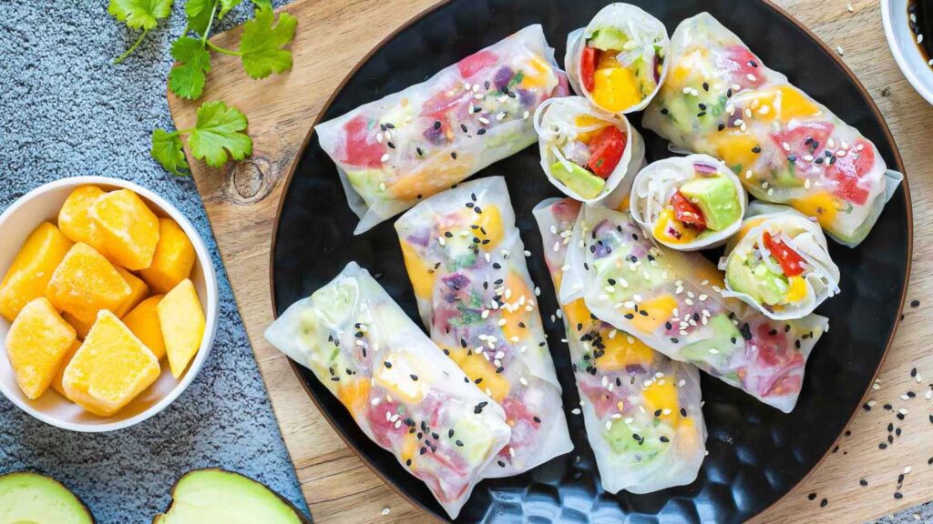 A black plate holds several avocado spring rolls.