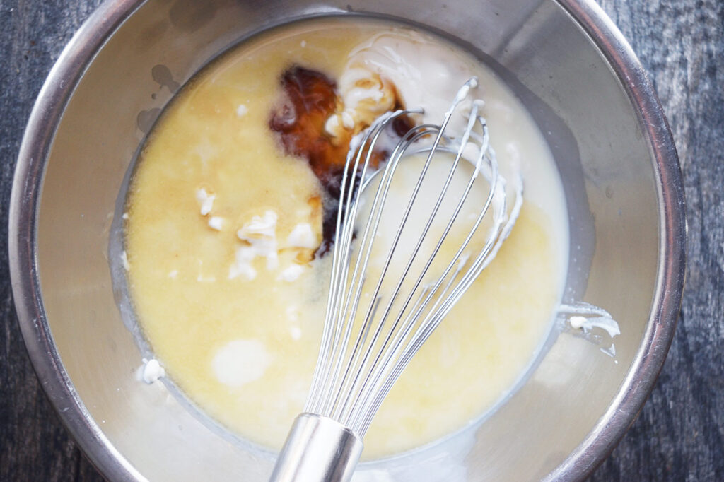 Baked Oatmeal wet ingredients in a mixing bowl with a whisk.