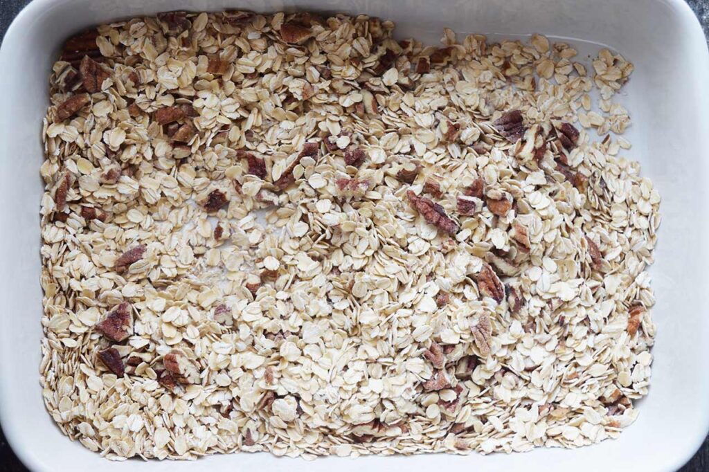 Oats, nuts, salt and baking powder in a white casserole dish, mixed together.